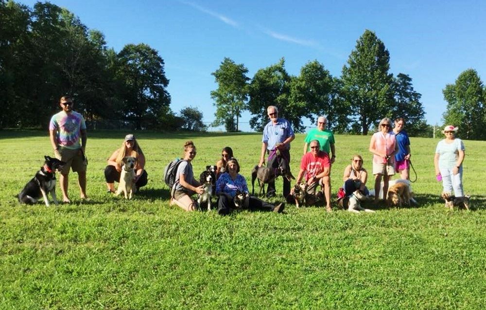 People and dogs gather at the proposed site of a dog park at Cane Creek Park.