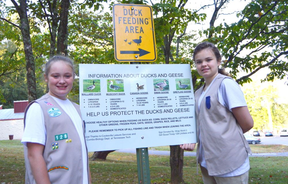 Girl Scouts show their duck feeding sign at Cane Creek Park.