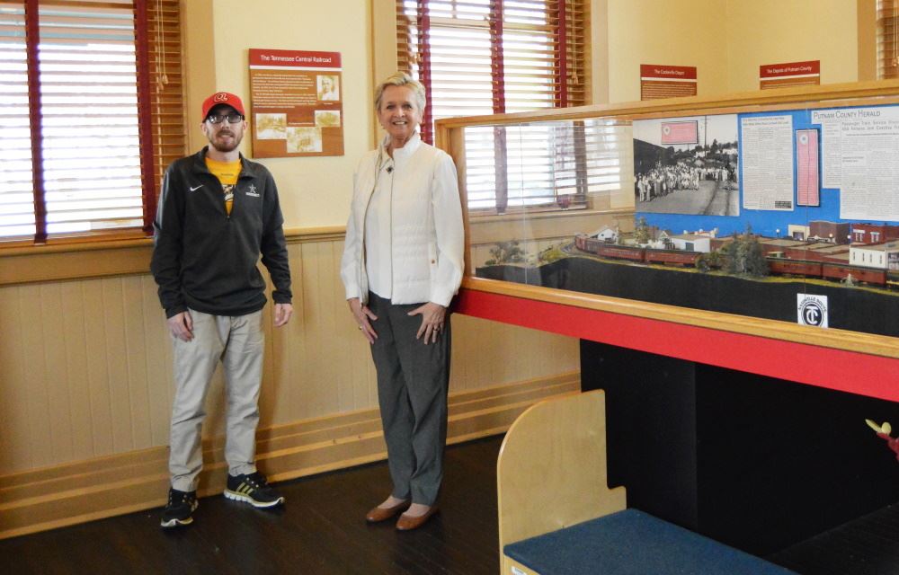 Two docents stand next to the model train at the Depot.