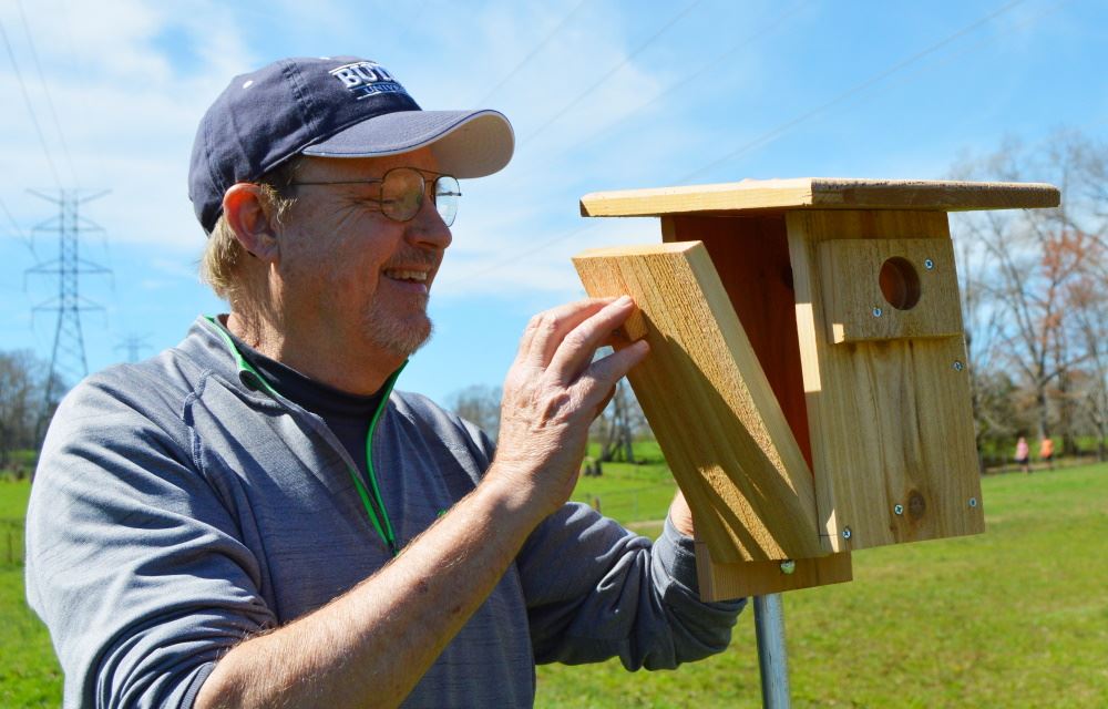 A man looks inside a bluebird box at Cane Creek Park