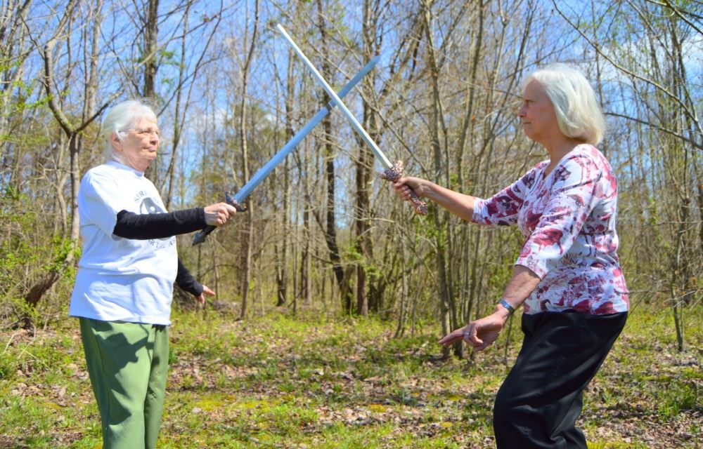 Susan Van Aalten, Nikki Desch and Barbara Sandlin show the World Tai Chi and Qigong Day sign.